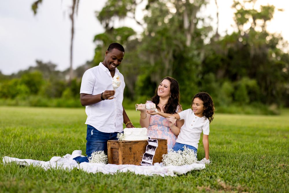 A picnic blanket with champagne glasses and food set up on grassy lawn during golden hour in a park setting.