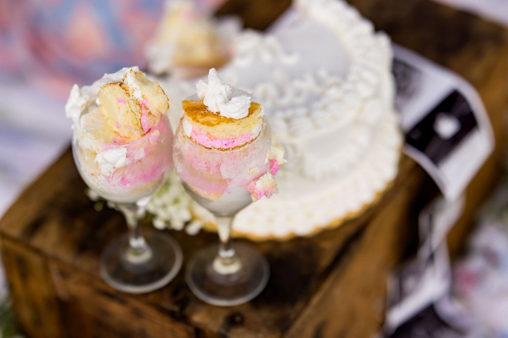 Pink champagne cocktails garnished with cotton candy float in delicate glasses at an elegant party setting.