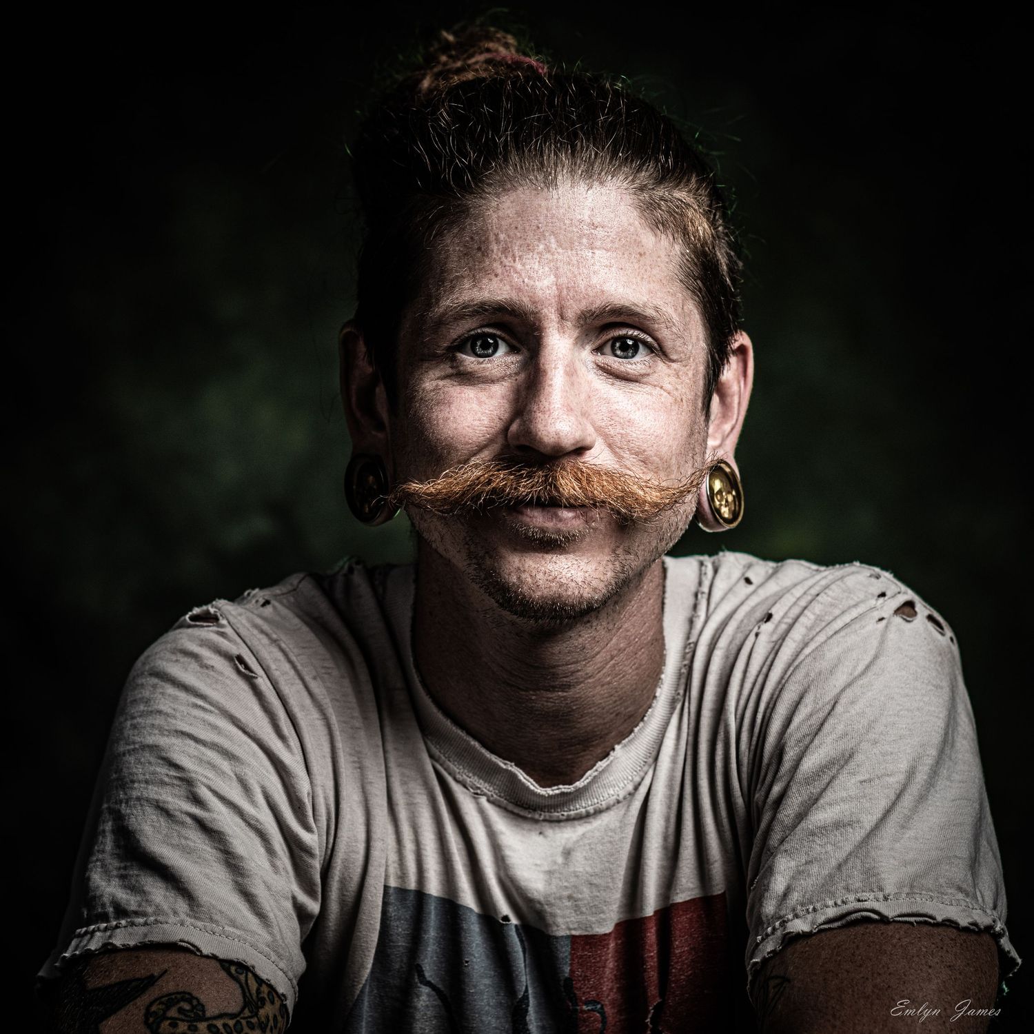 Close-up dramatic photo series showing person in a gray shirt with a unique handlebar mustache and dramatic lighting.