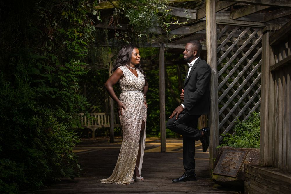 Couple sharing romantic moment on wooden garden walkway surrounded by greenery.