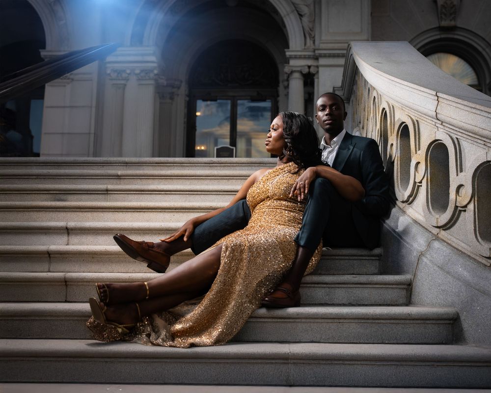 A couple shares a romantic moment on marble steps in a grand indoor setting with dramatic lighting on library of congress steps.
