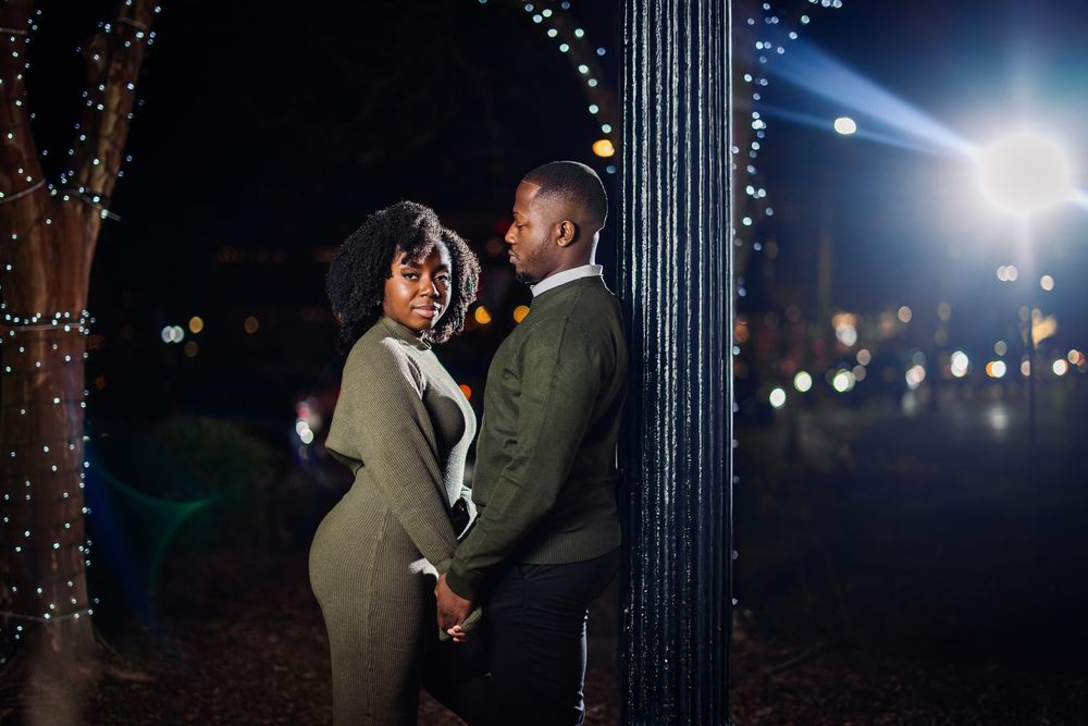 A romantic nighttime scene with string lights creating a magical atmosphere for an embracing couple.