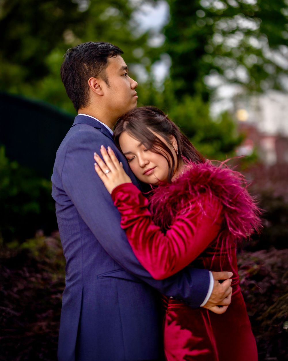 Couple embracing outdoors, with one wearing a striking red feathered outfit.