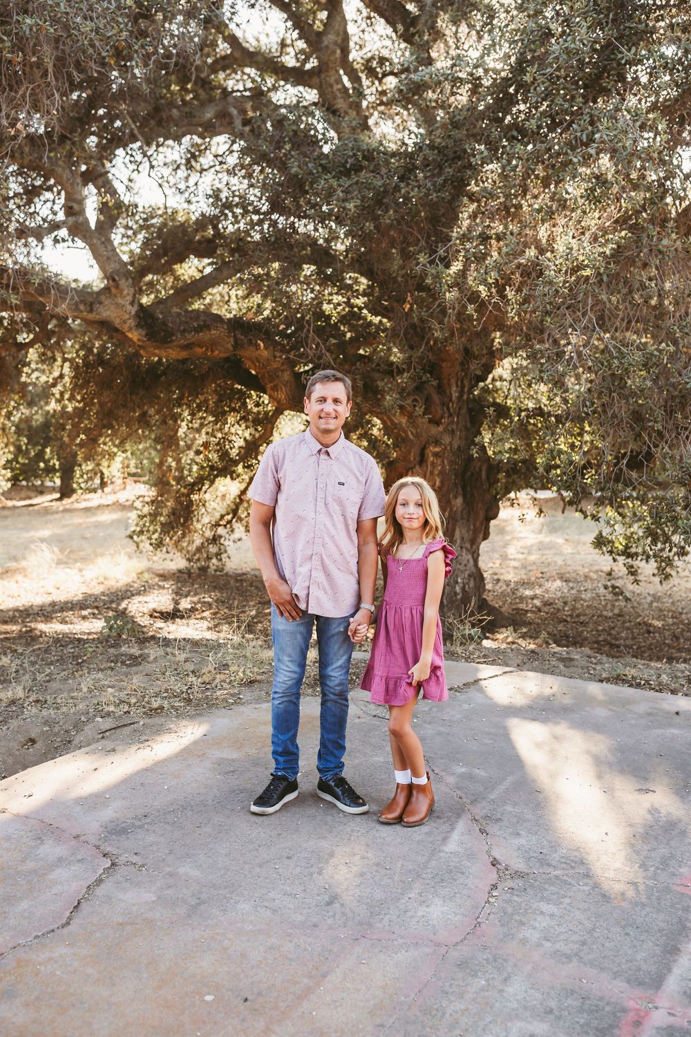 Five progressive photos show a tender moment between two people in matching pink and blue outfits under oak trees.