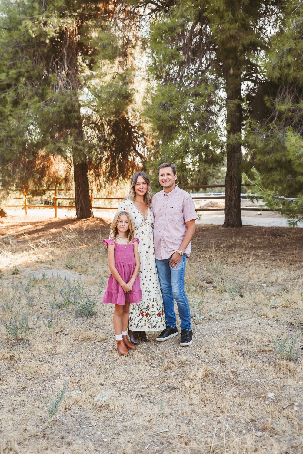 A family enjoys time together outdoors in a wooded area with pine trees on a sunny afternoon.
