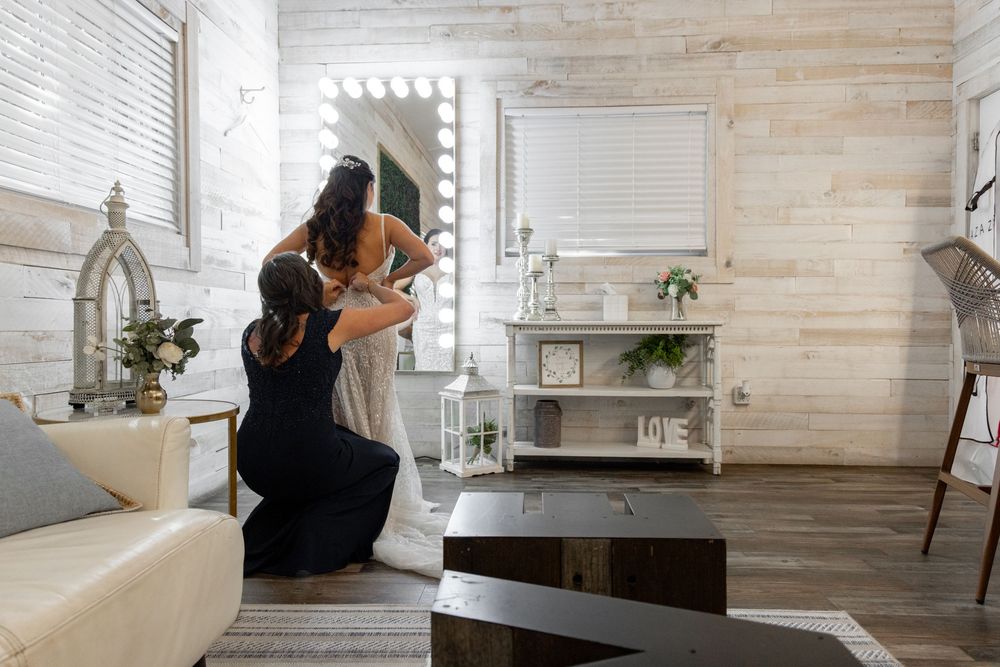 A makeup artist applies cosmetics in a bright modern room with wooden walls and vanity lighting.