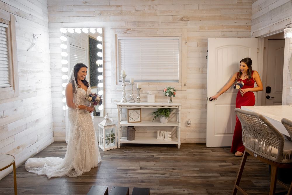 Two women in a rustic room with wooden walls, vanity lighting and modern decor.