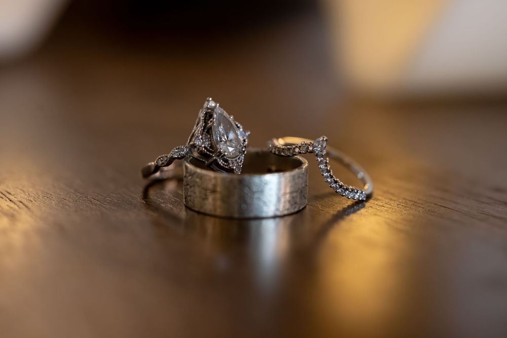 Wedding rings and engagement ring sparkle on a wooden surface in warm lighting, creating a romantic composition.