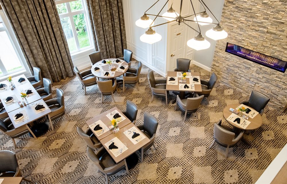 Modern office workspace with geometric patterned carpet, wooden desks, and pendant lighting in an open floor plan layout.