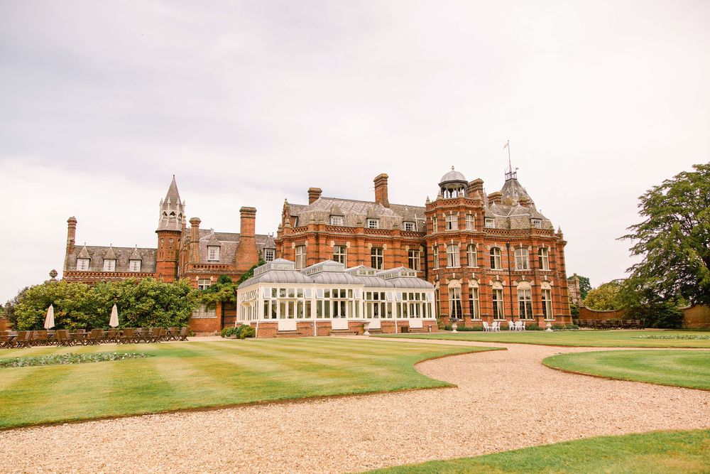 Panoramic view of a historic red brick mansion with manicured golf course grounds and rolling hills.