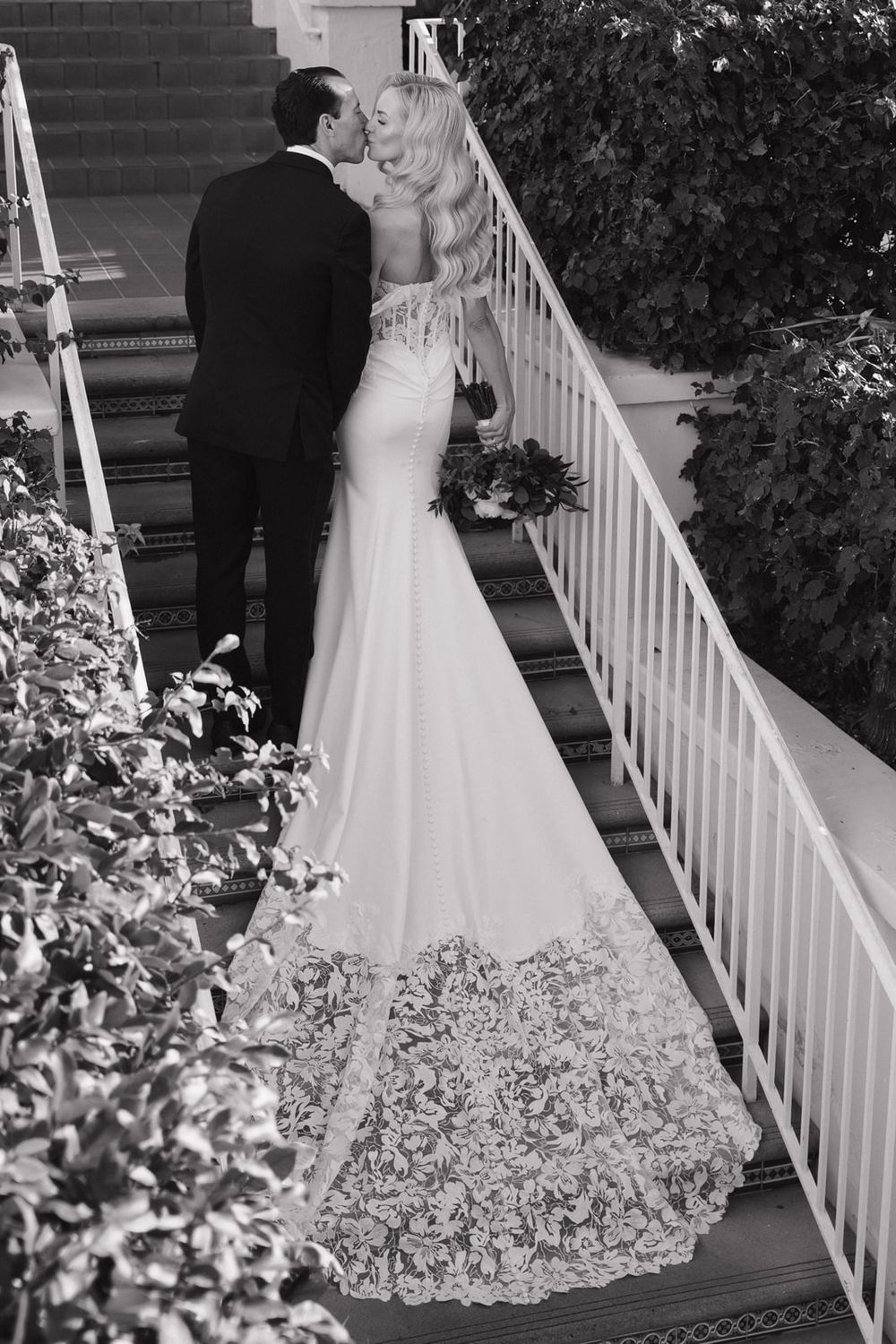 Black and white wedding photo sequence showing bride and groom descending white stairs with floral decorations.