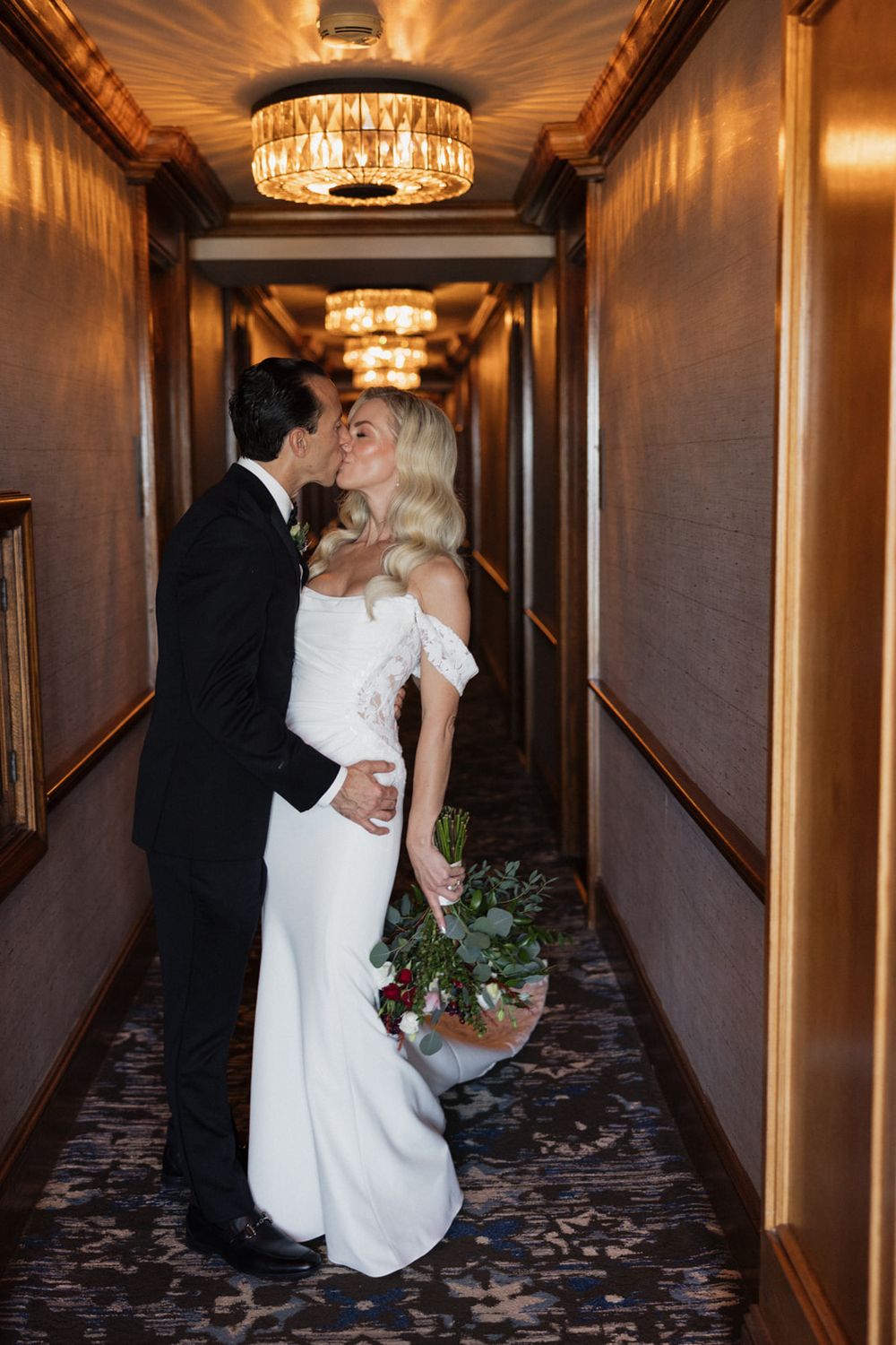 A romantic wedding moment captured in a hotel hallway with elegant lighting and decor.
