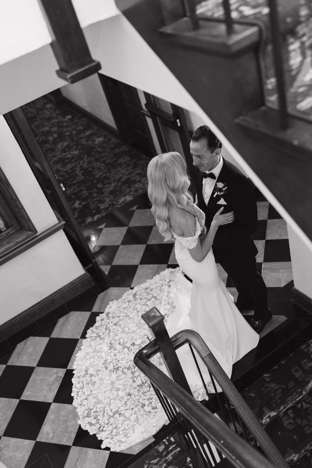 A bride and groom share an intimate moment on a black and white checkered staircase during their wedding.