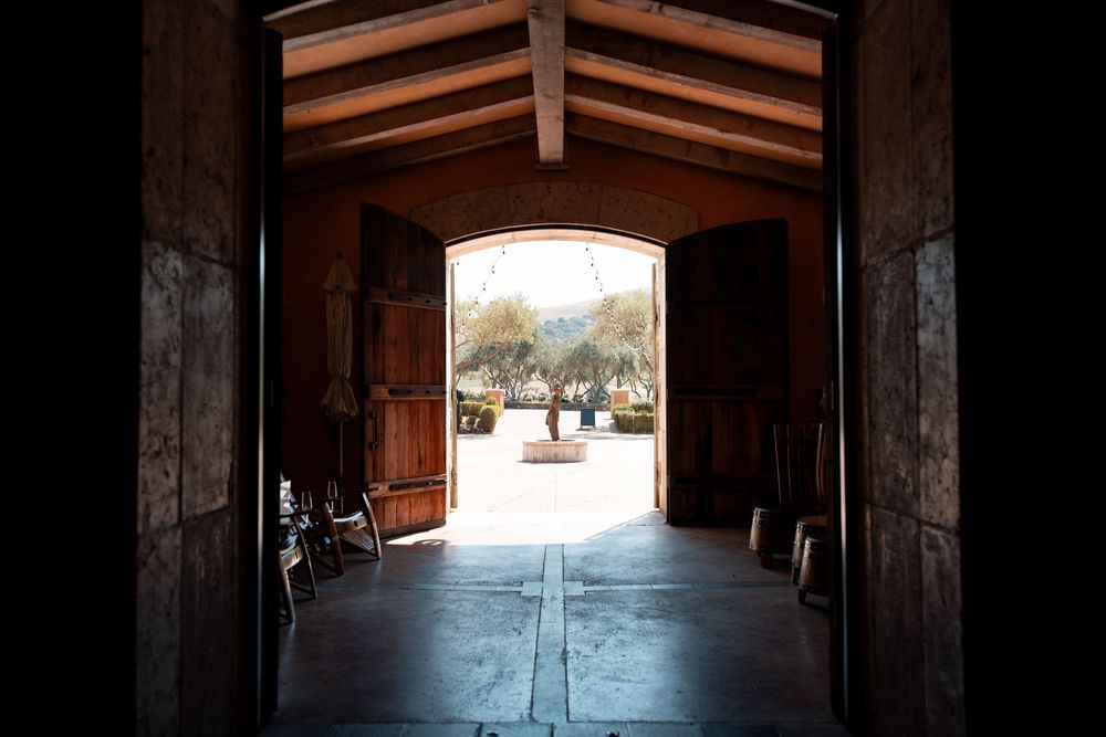 Interior view of a long wooden barn hallway with sunlight streaming through the entrance at the far end.