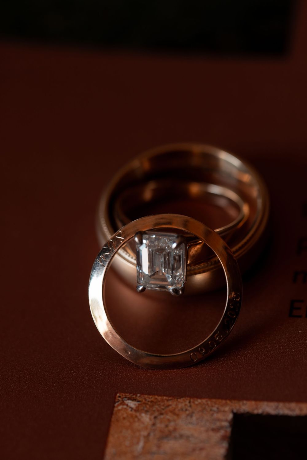 Macro photography sequence shows a diamond engagement ring on a rich brown textured background in varying angles.
