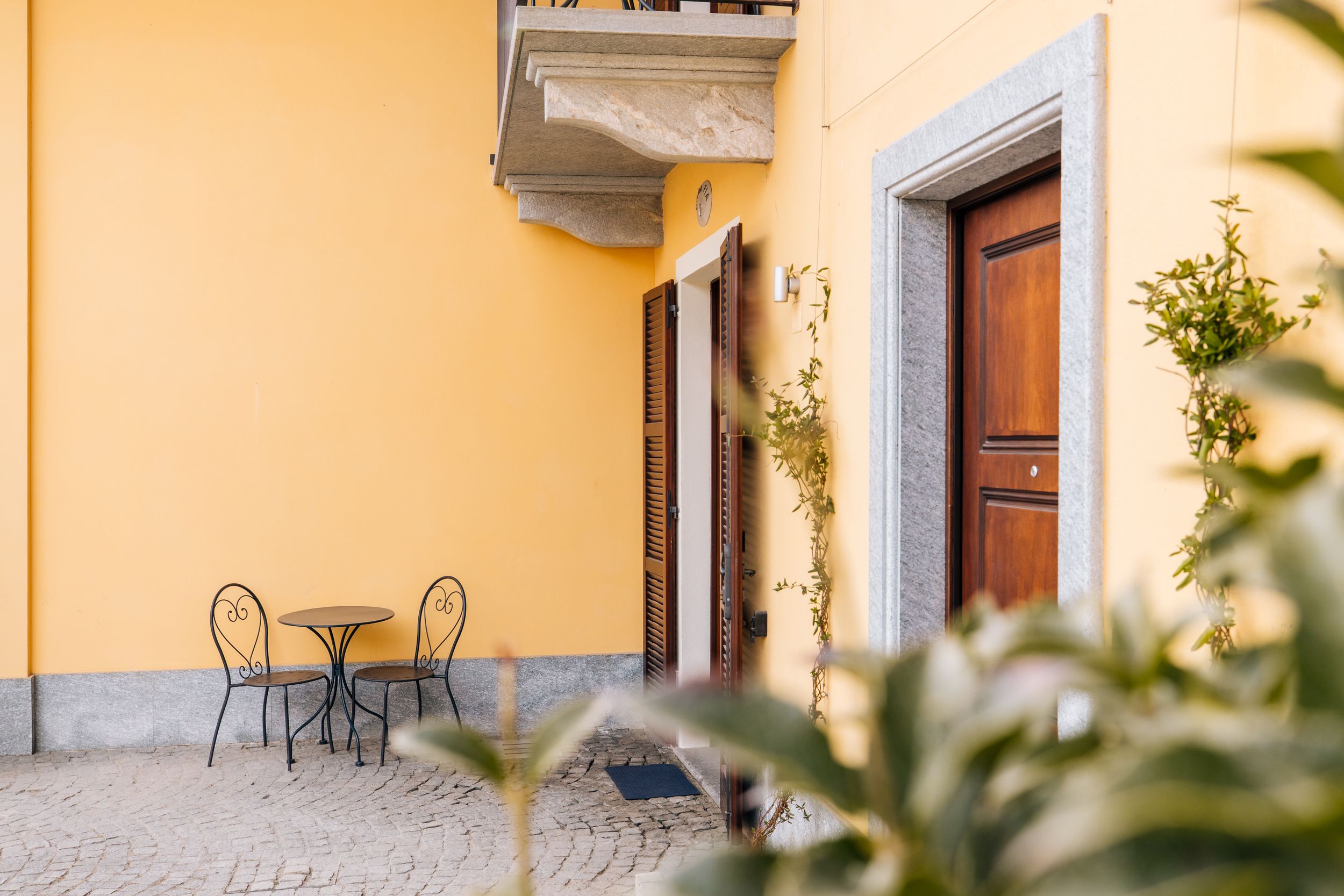 Bright yellow building facade with wooden doors and decorative stone archways in a Mediterranean architectural style.