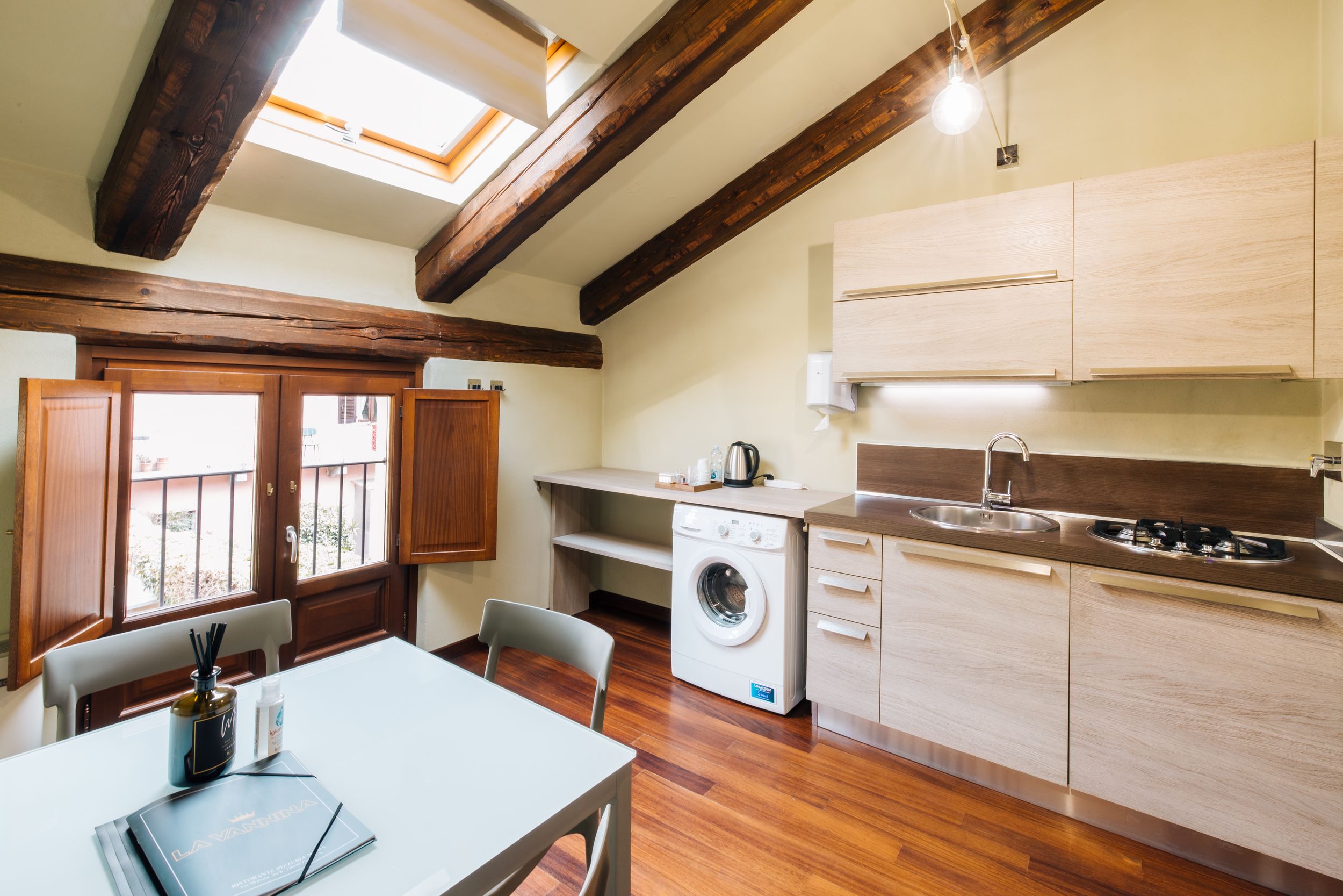 Bright modern kitchen interior with wooden beams, skylight, and hardwood floors in open concept design.