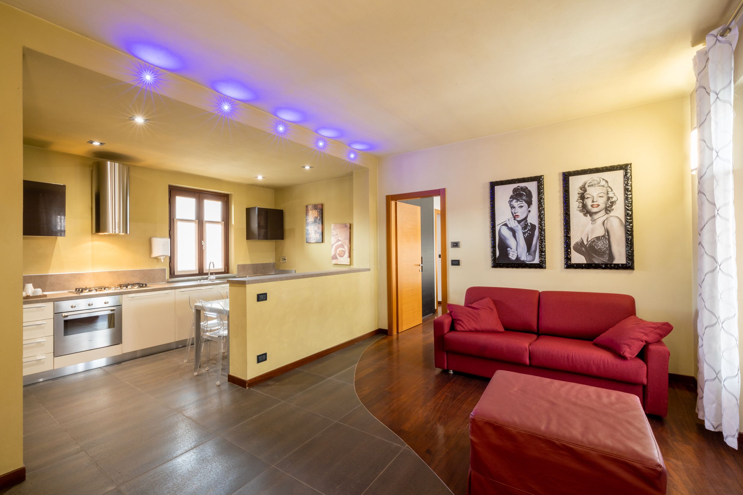 Modern basement renovation with blue LED accent lighting and burgundy sectional sofa in an open concept space.