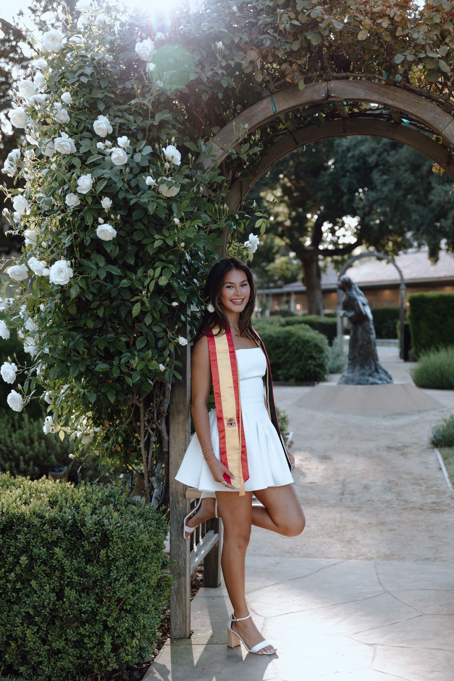 Santa Clara University graduate poses for her grad photoshoot by standing under an archway. Taken by Bay Area Graduation Photographer.