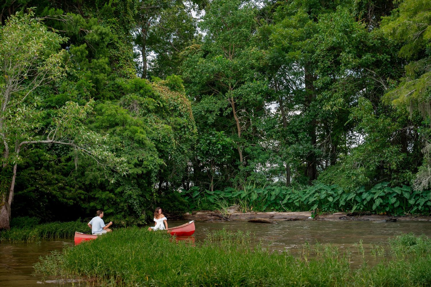 Two red canoes float peacefully on a serene river surrounded by lush green forest.