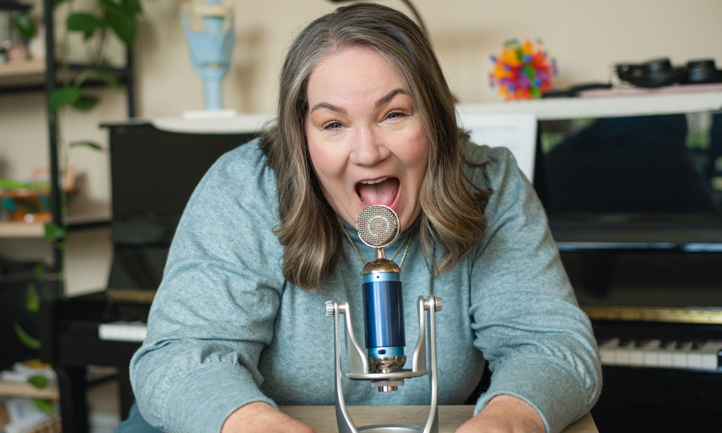 Recording artist enthusiastically singing into a blue microphone in a home studio setting.