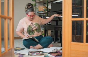 Someone sketching or journaling while surrounded by plants in a cozy indoor setting.