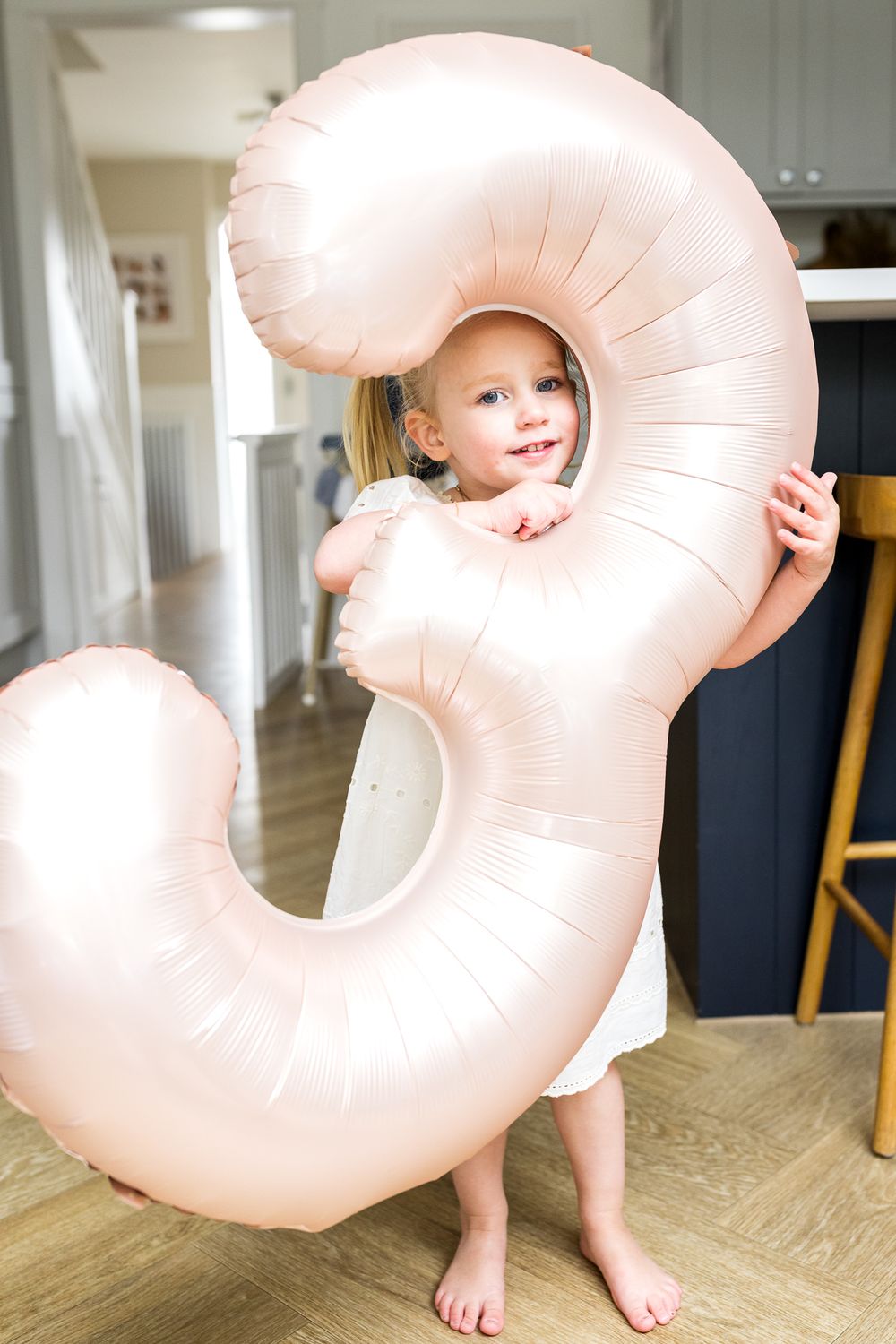 birthday girl holding a helium balloon with number three