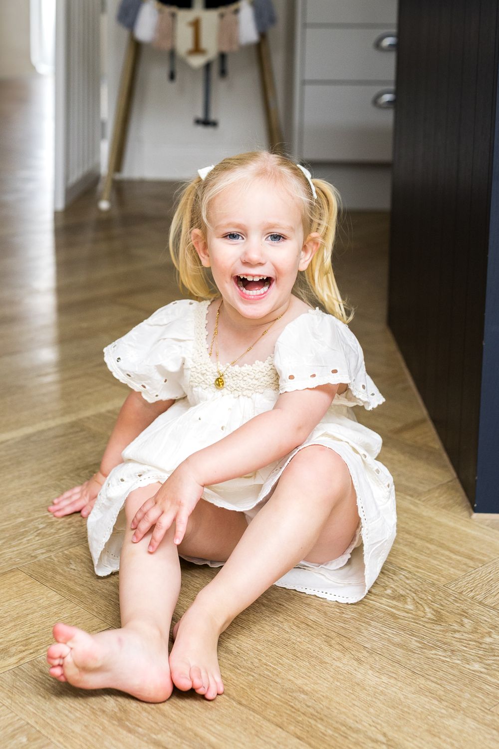toddler girl sitting on the floor laughing at the camera