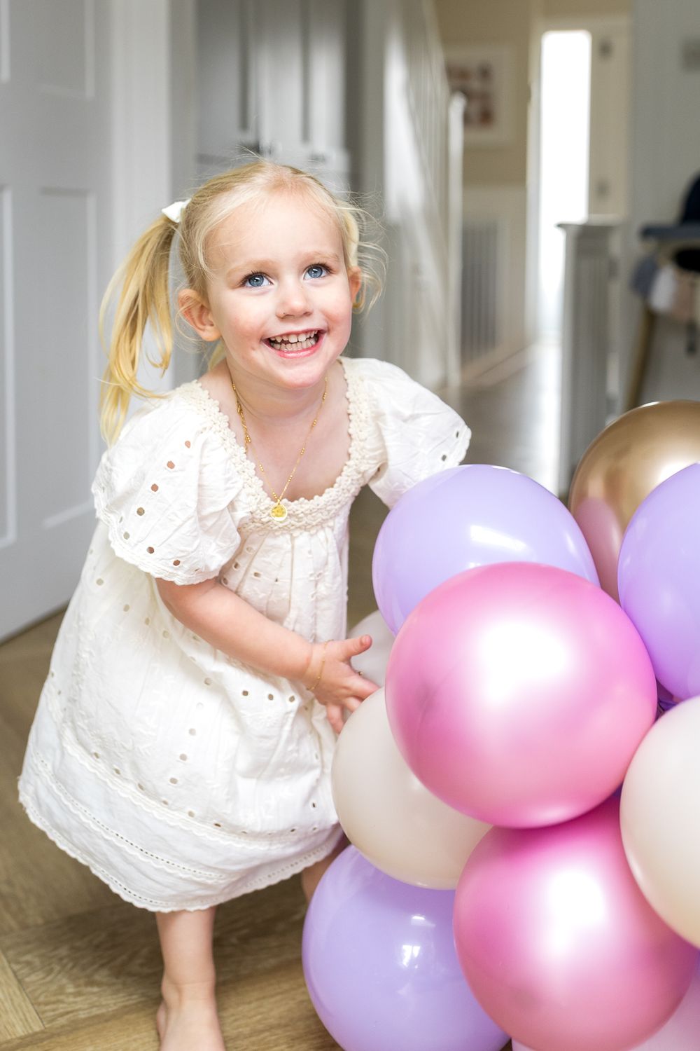 little girl playing with pink birthday balloons