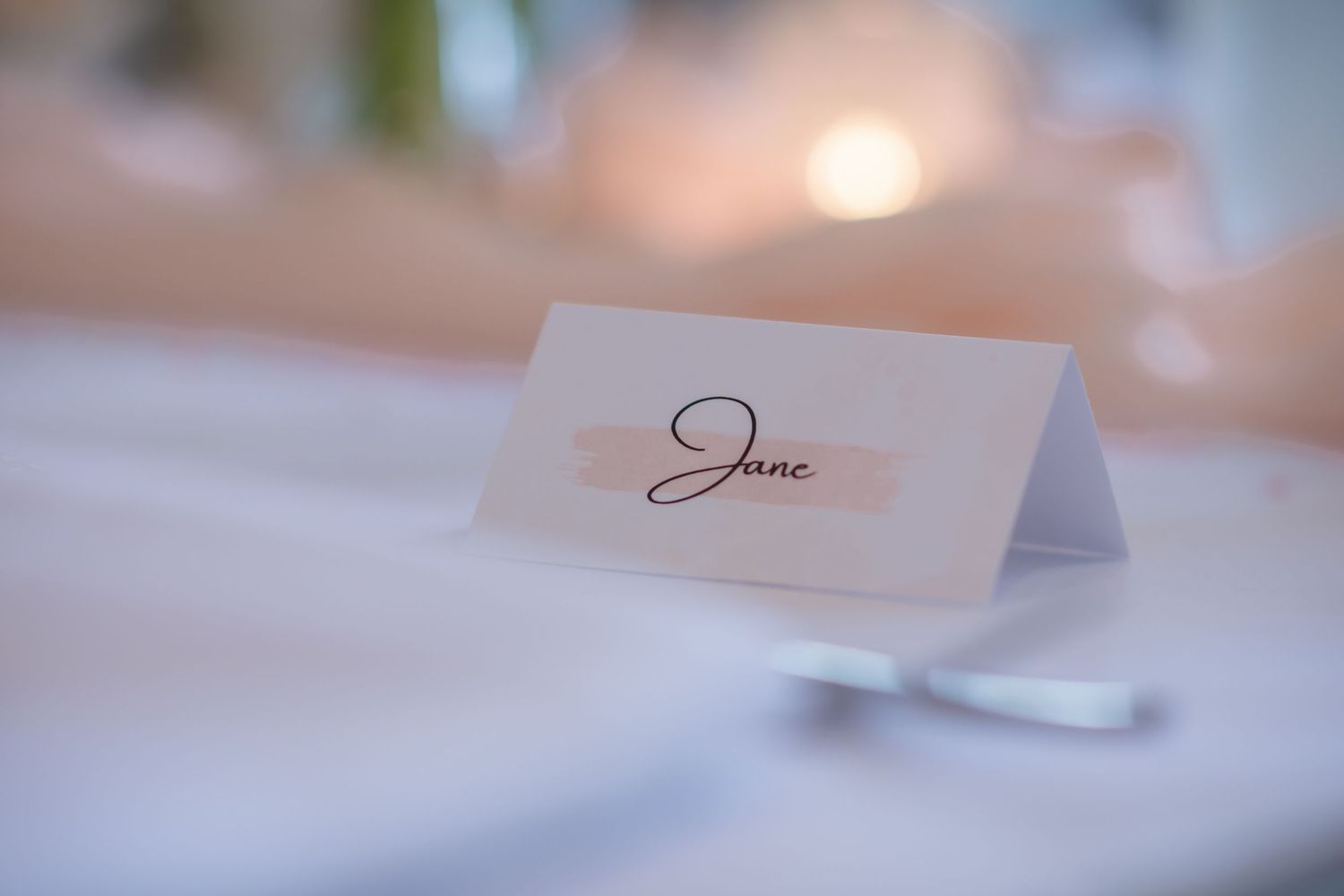 Elegant wedding reception table settings with soft pink floral centerpieces and glowing candles create a romantic atmosphere.