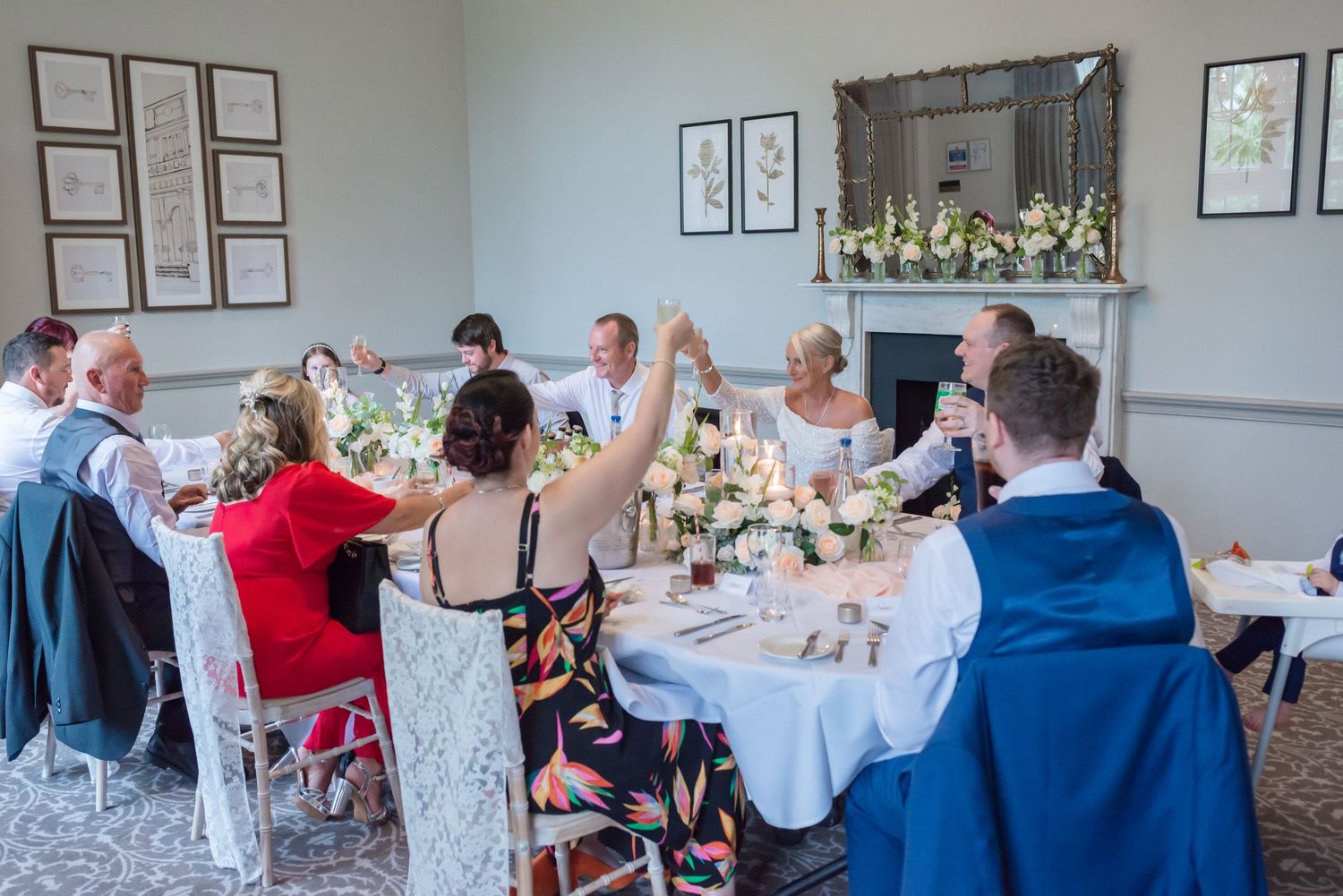 Wedding guests seated at round tables during reception celebration in an elegant dining room.