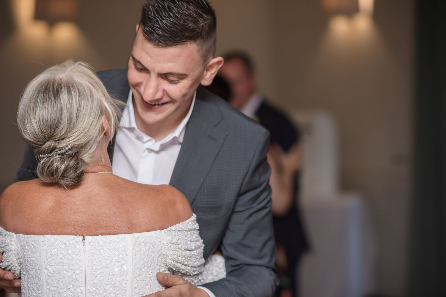 A bride and groom share an intimate moment during their first dance at an elegant indoor wedding reception.
