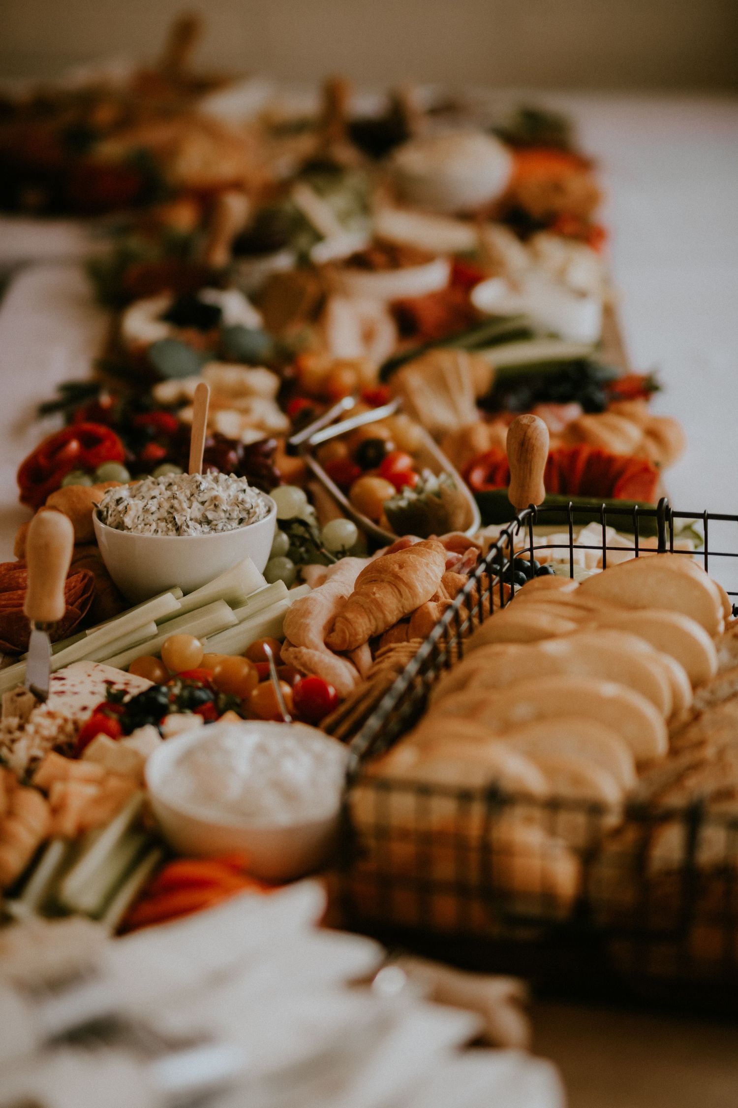 Elegant charcuterie board spread with assorted meats, cheeses, dips, and garnishes arranged on wooden serving platters.