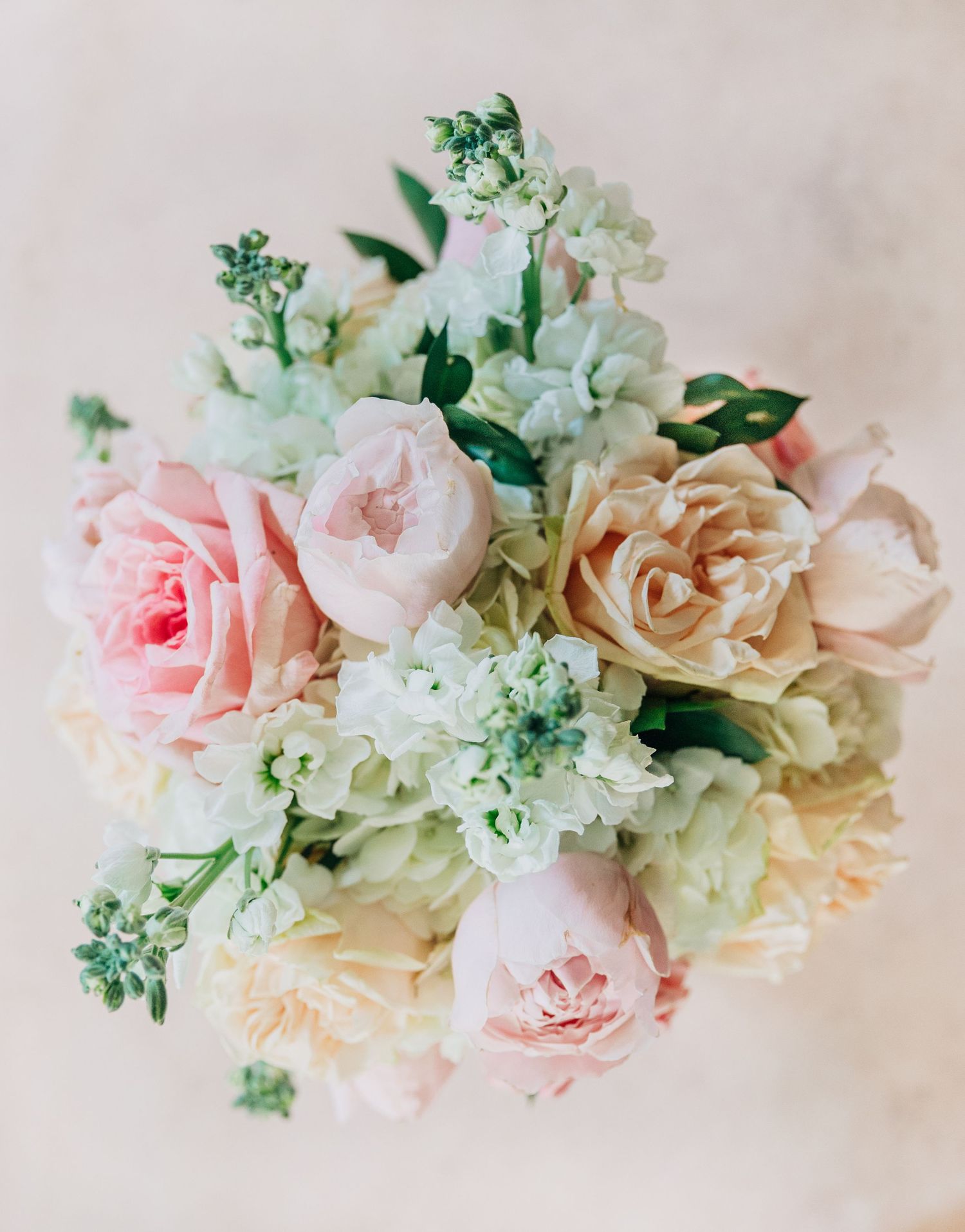 Delicate floral arrangement featuring blush pink roses and white flowers with greenery against a neutral background at The Wildflower 301