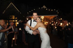 A couple dances together at an evening wedding reception with sparklers and string lights creating a romantic ambiance.