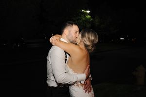 A couple shares a romantic embrace during a nighttime outdoor wedding celebration.