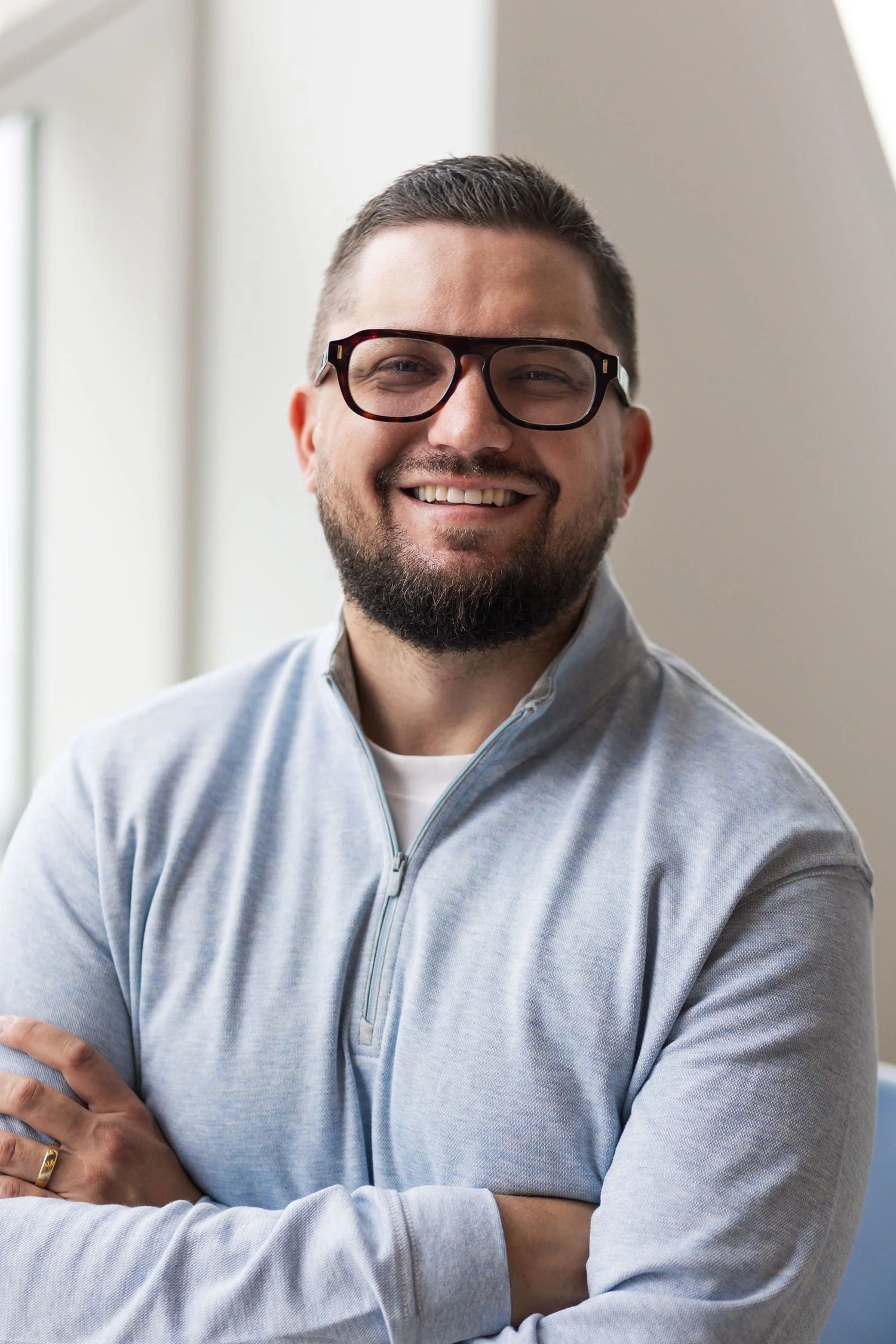 Collage of someone wearing glasses and a grey sweater showing different expressions and poses against white background.