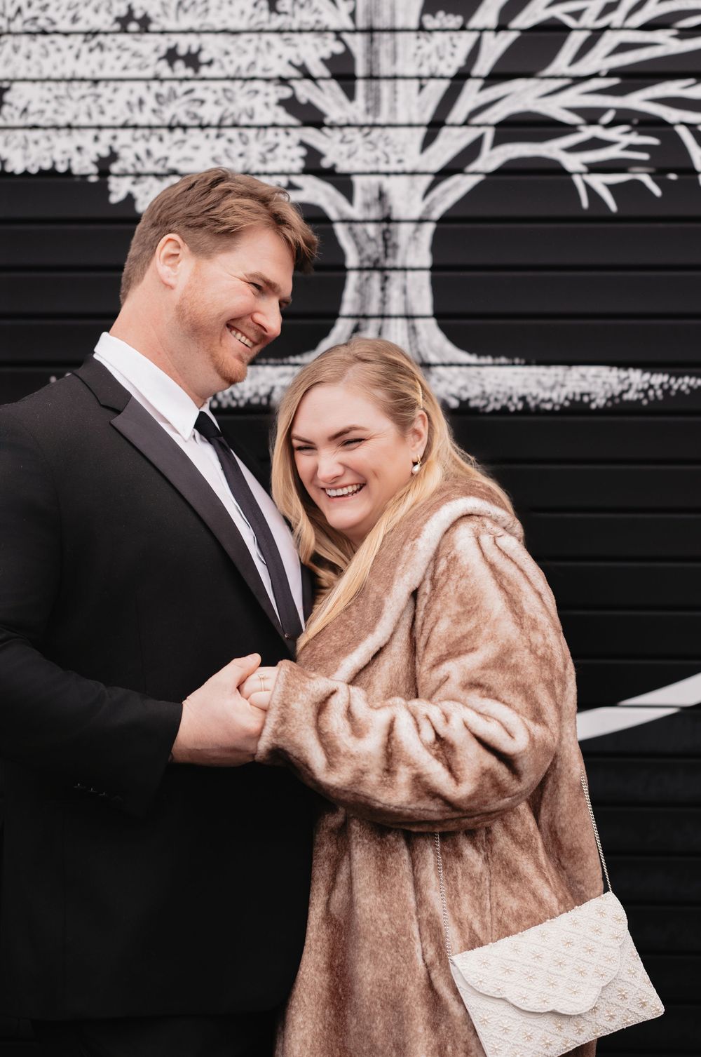 A couple shares intimate moments while wearing formal attire and a blush-colored fur coat.