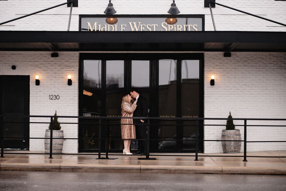 Modern storefront exterior with black pendant lights and white brick walls along a covered walkway.