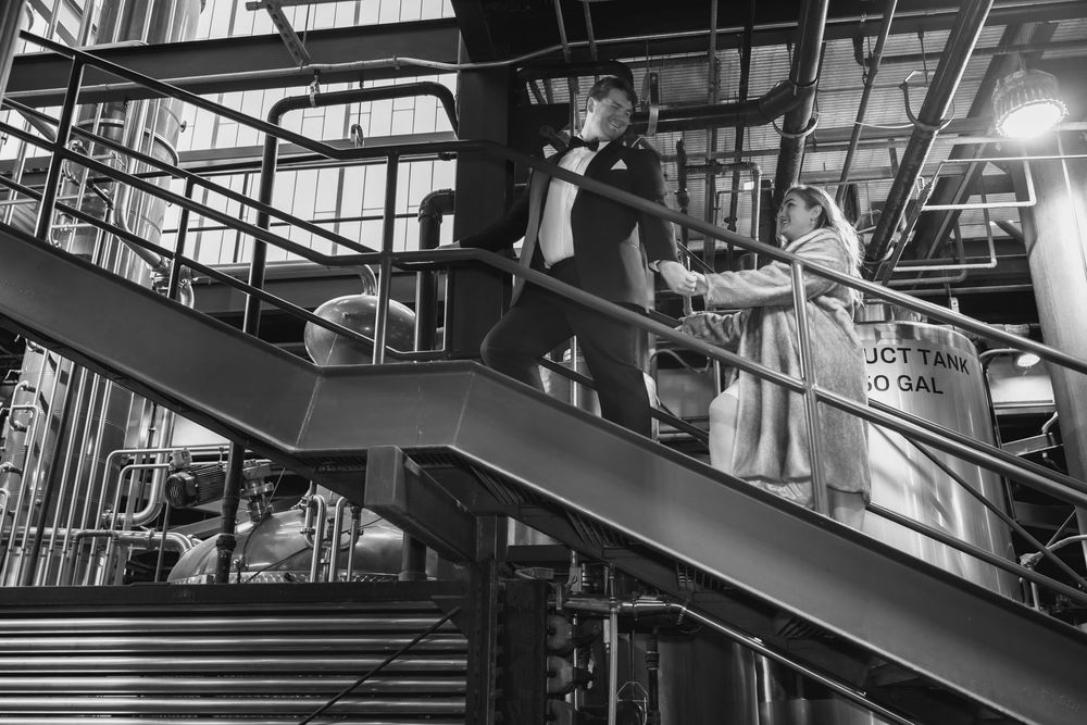 A black and white photograph shows people descending a modern industrial staircase with metal railings.