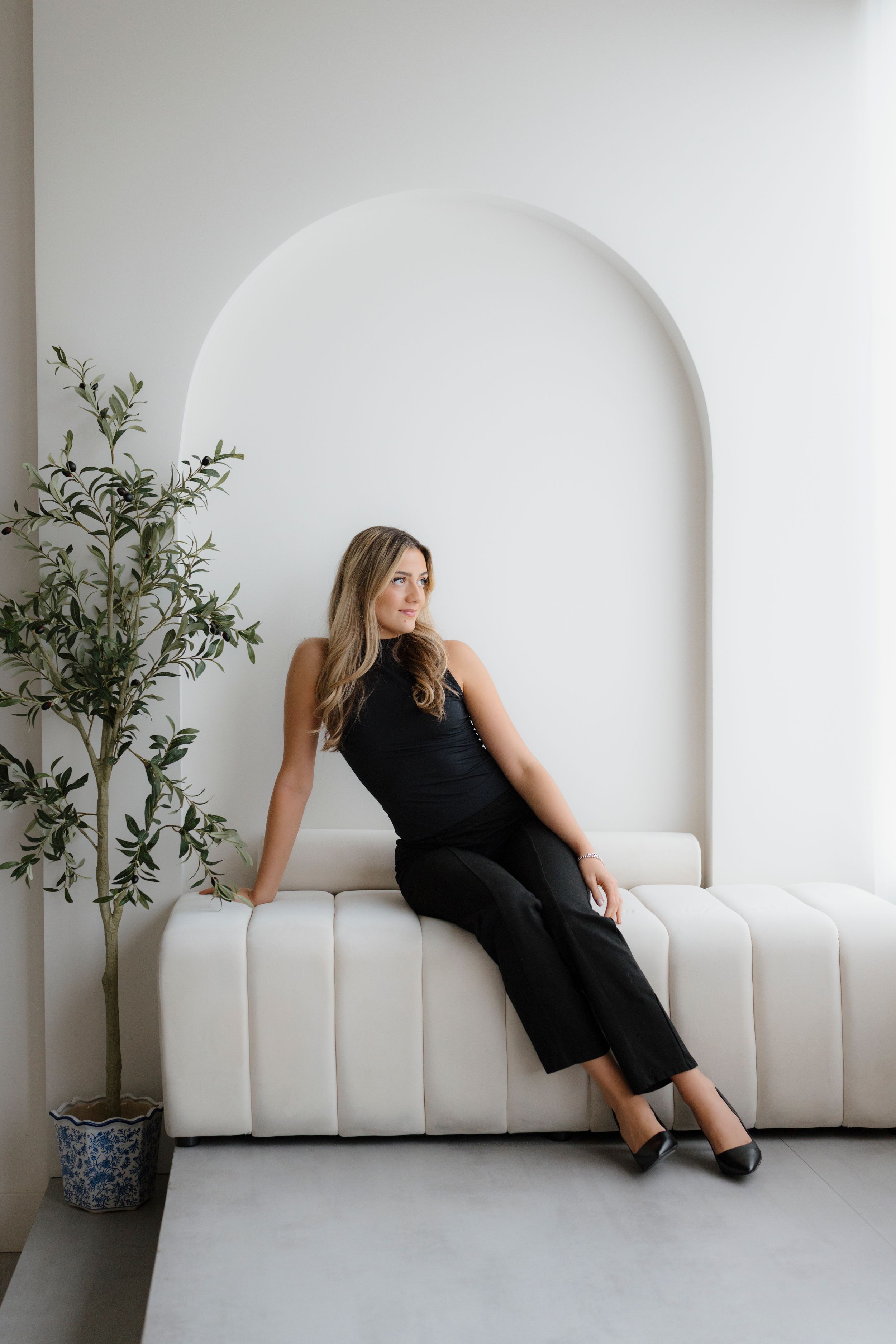Minimalist white interior with curved bench seating and potted plants creating a serene atmosphere.