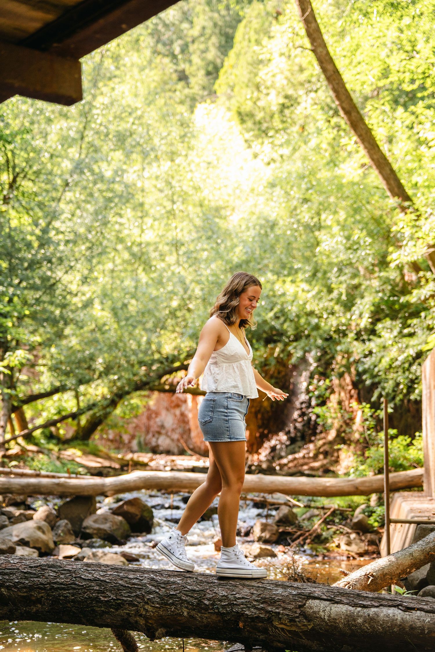 A sequence of photos shows someone sitting on a fallen log by a stream in a sunlit forest setting.