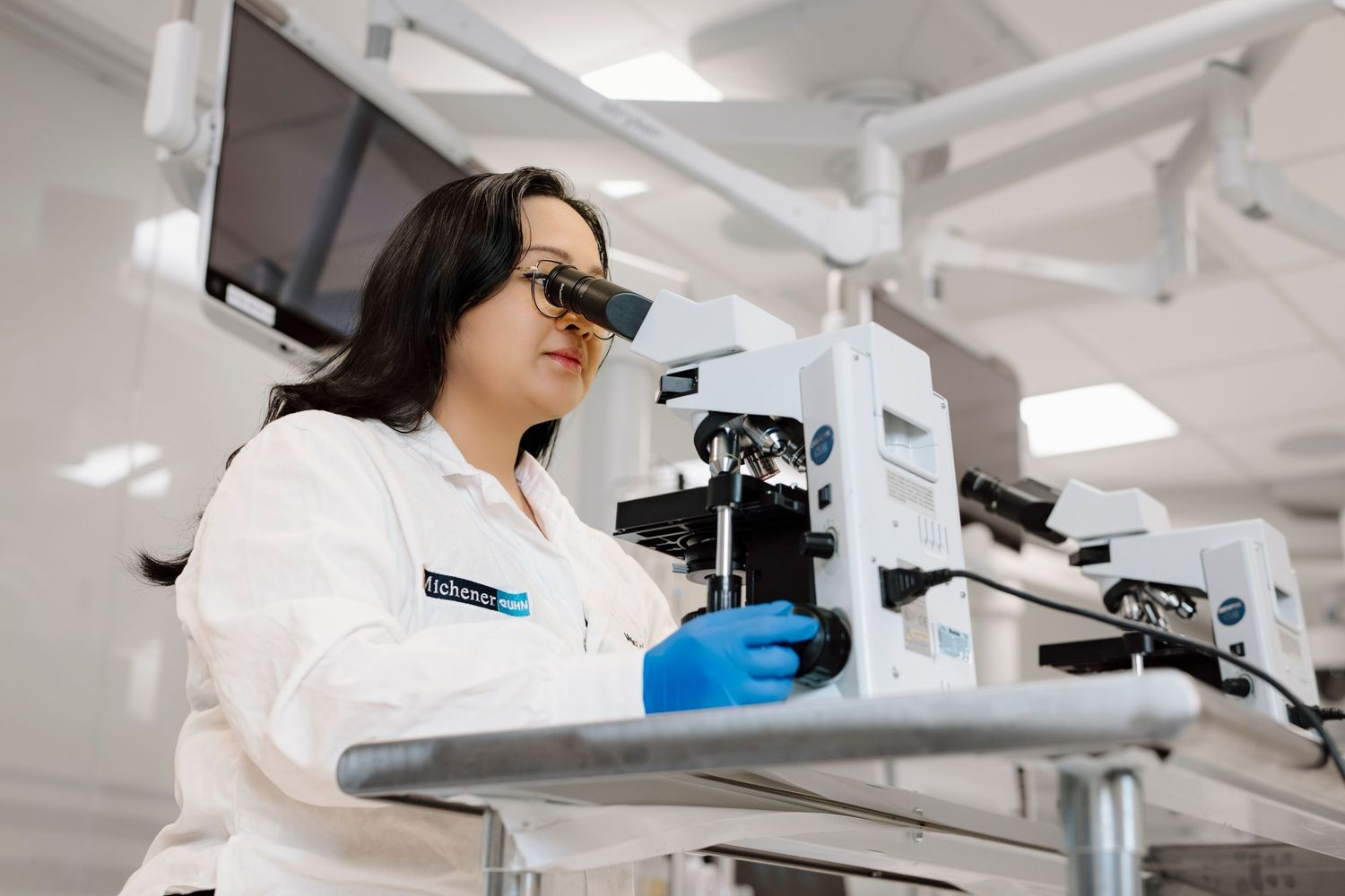 Dental student examining equipment in a modern dental operatory with bright lighting and advanced technology.