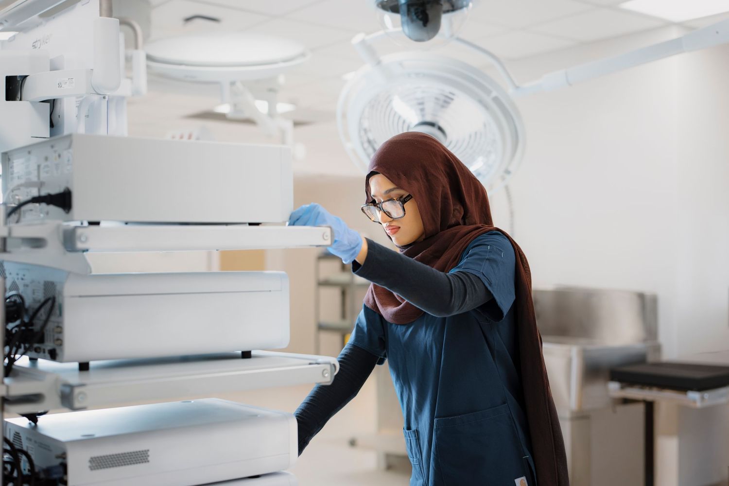 Healthcare worker operating dental equipment in a sterile white medical environment.
