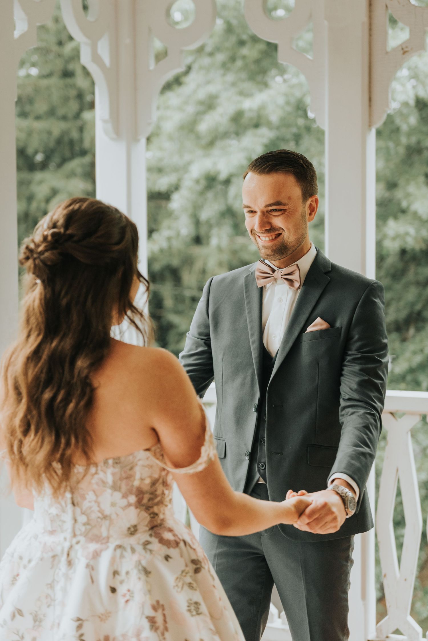 A couple shares a tender first look moment on their wedding day in a sunlit gazebo.