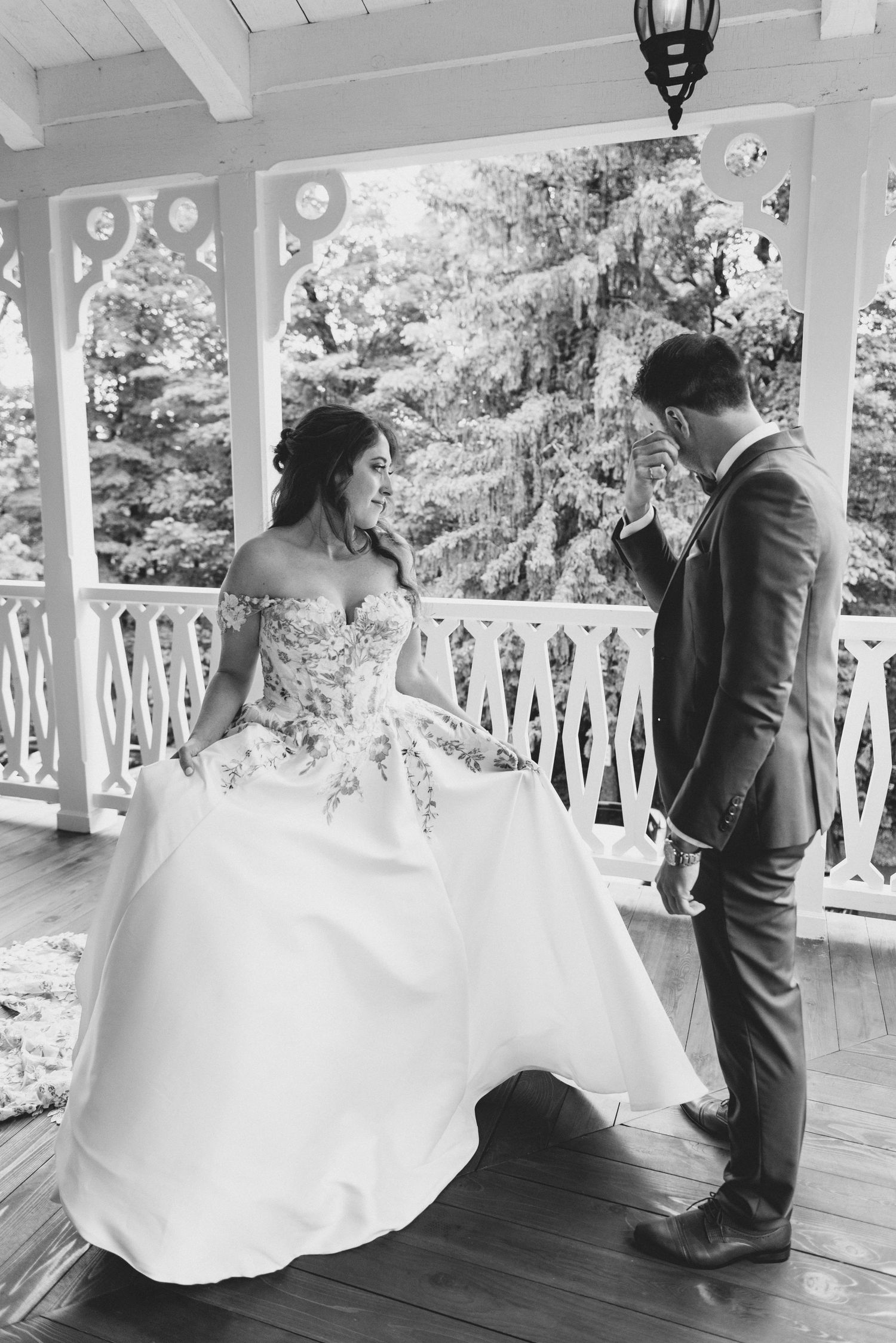 A romantic moment captured on a white porch with a couple in wedding attire sharing a tender moment.