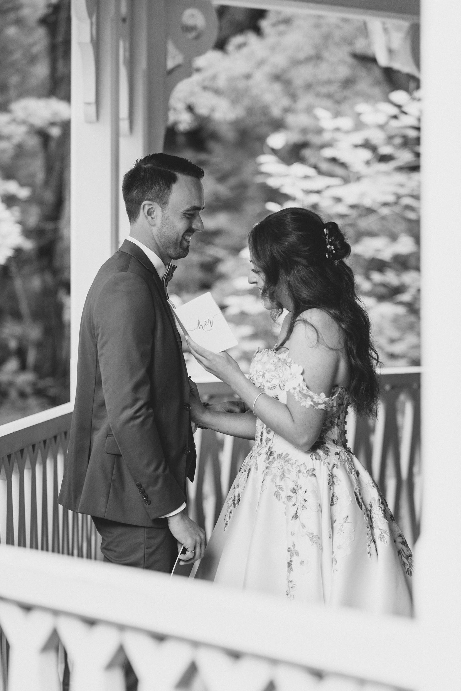 A romantic wedding couple shares intimate moments on a white porch during their first look photo session.