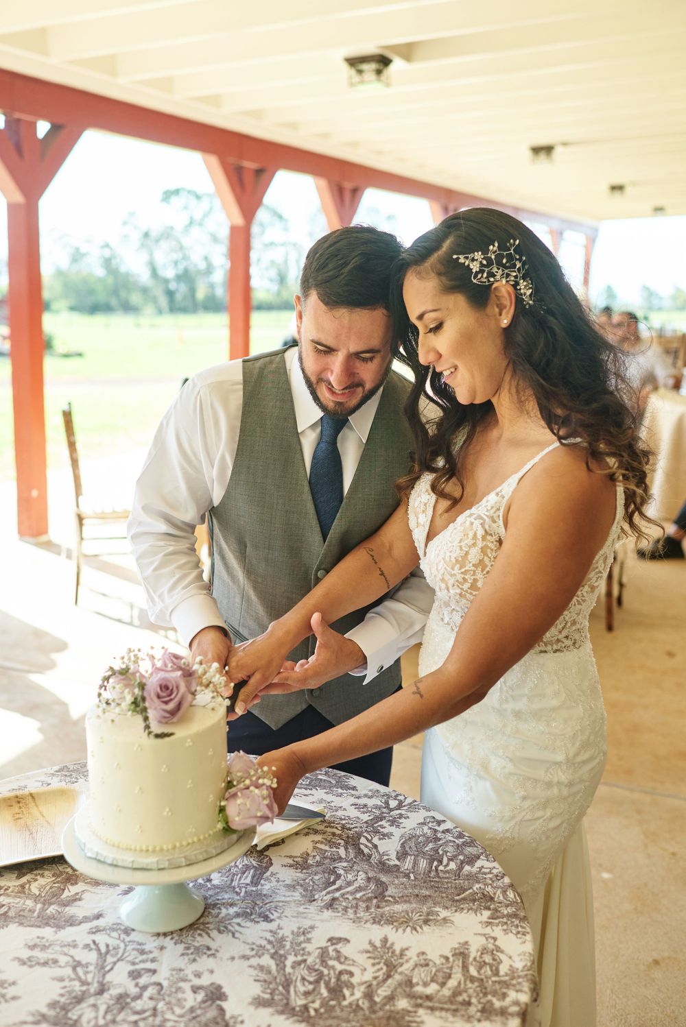 Newlyweds cutting their elegant white wedding cake together during reception.