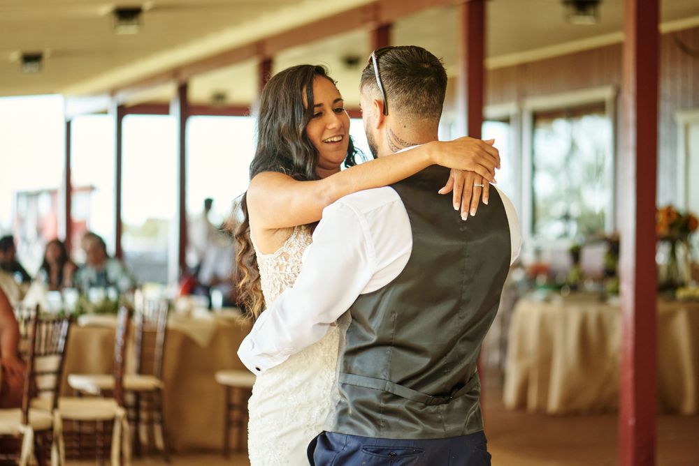 Couple sharing their first dance in a rustic covered venue with natural lighting.