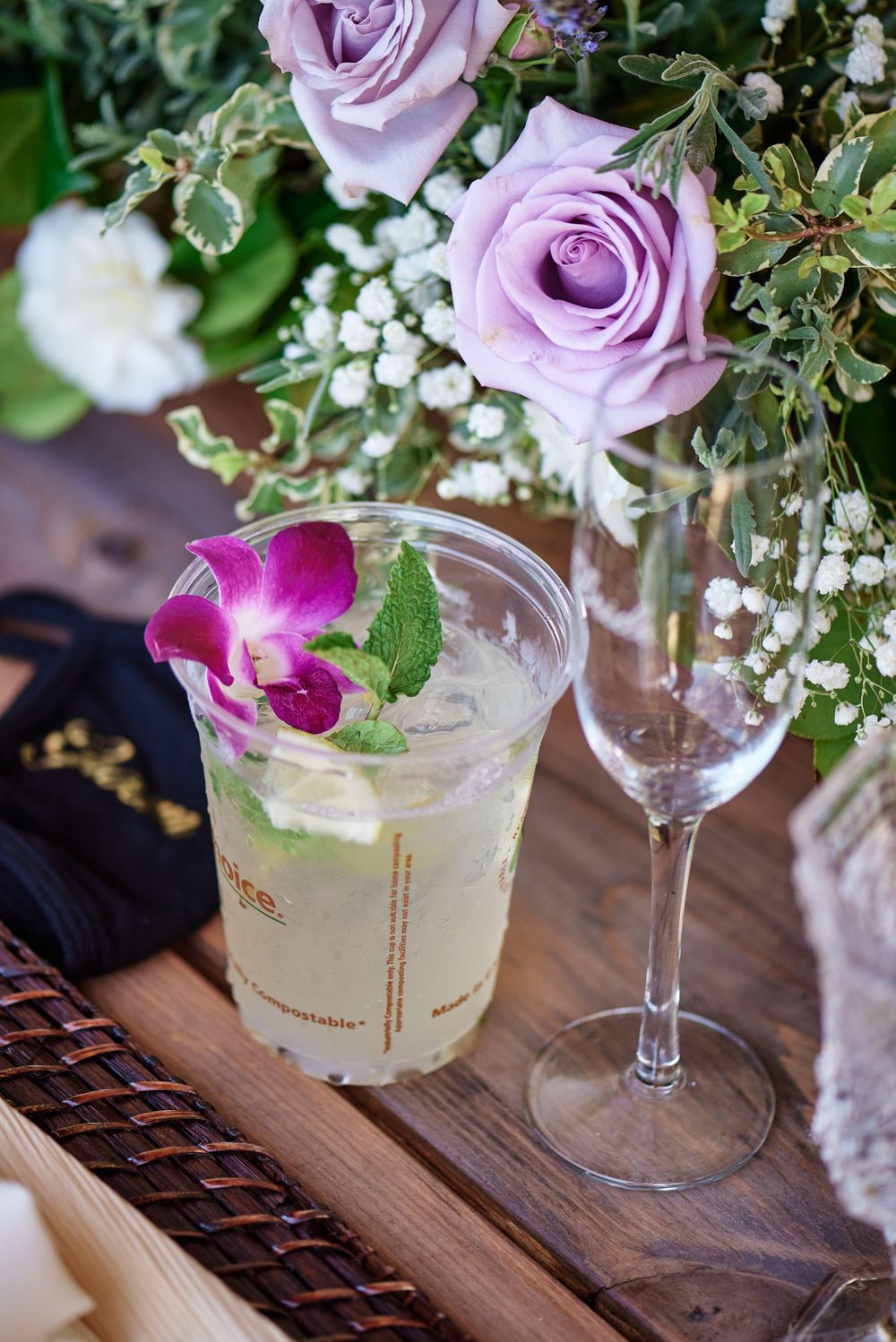 Elegant cocktails garnished with purple roses and orchids on a wooden table.
